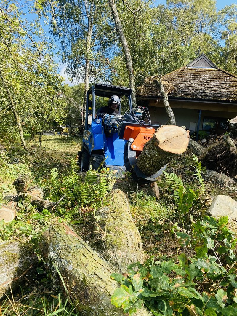 Multi One mini-loader gripping a felled log next to a Highland property
